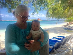 Grandmother and baby on shaded tropical beach.